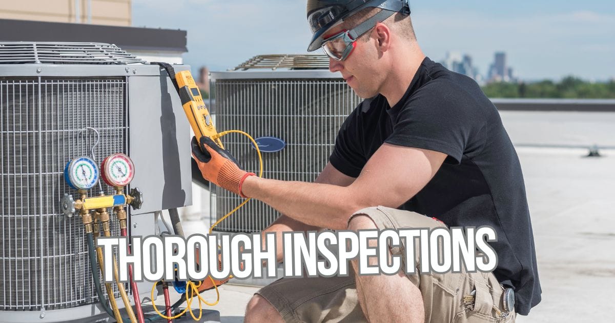 Man on the roof with electronic tools inspecting one of two hvac units